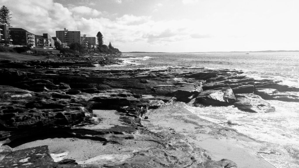 Coastal rockpools with surf washing over the rock platform. Photo: One Woman's Notebook.
