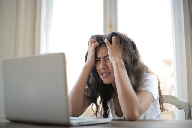 Stressed woman looking at computer with hands in her hair, concerned about online scams and Gumtree safety. Photo by Andrea Piacquadio from Pexels