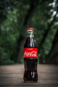 Coca-Cola bottle, pictured on the ground. Photo by Artem Beliaikin from Pexels.